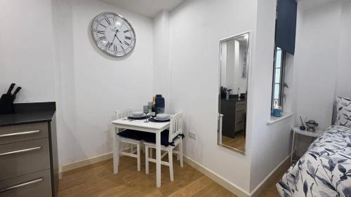 a room with a table and a clock on the wall at Chic Studio near Canary Wharf in London