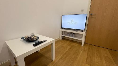 a living room with a tv and a table with a television at Chic Studio near Canary Wharf in London