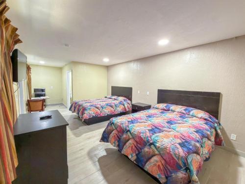 a hotel room with two beds and a desk at Vanguard Motel in Ormond Beach