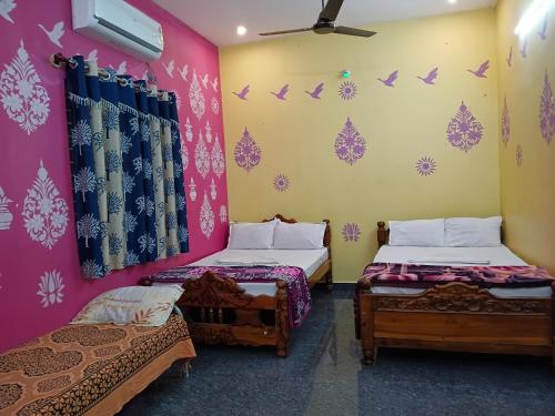 two beds in a room with pink walls at Vibheeshan Villa in Yelagiri