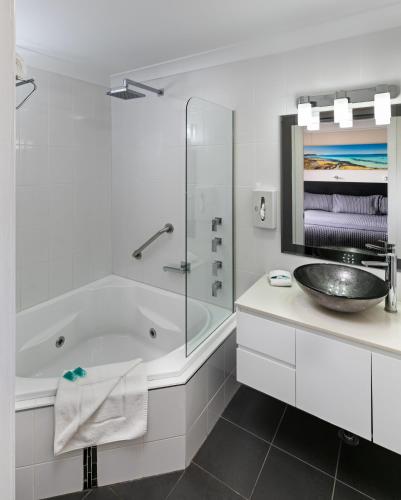 a white bathroom with a tub and a sink at Dolphin Shores in Vincentia