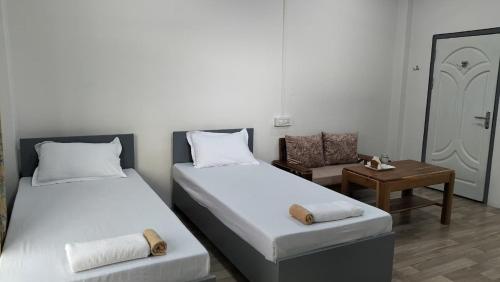 two beds in a room with a table and a chair at Zosang Homestay in Āīzawl