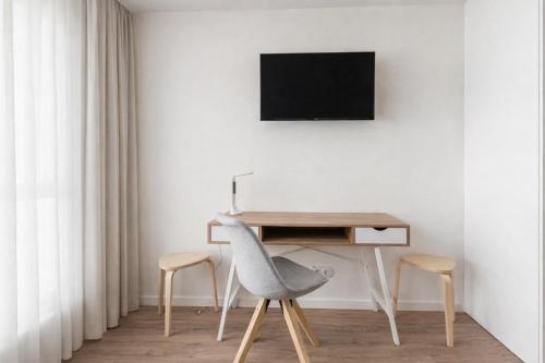 a desk and two chairs in a room with a television at Magnolia Suites & Stays in Porto