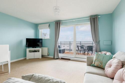 a living room with a couch and a television at Ocean Breeze - Stunning Harbour Views from Private Balcony in Poole