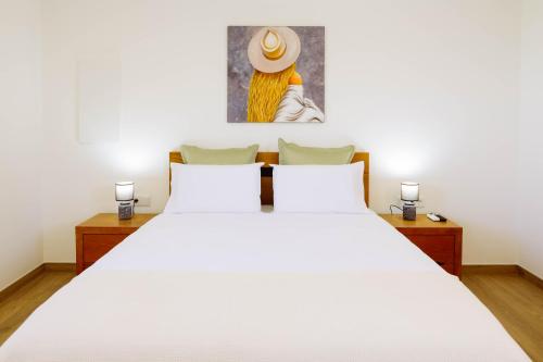 a bedroom with a large white bed and a painting at Casa Fundevila Celorico de Basto in Celorico de Basto