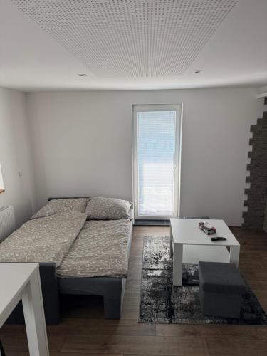 a white room with a bed and a table at Apartmán u Trojáků in Pozlovice