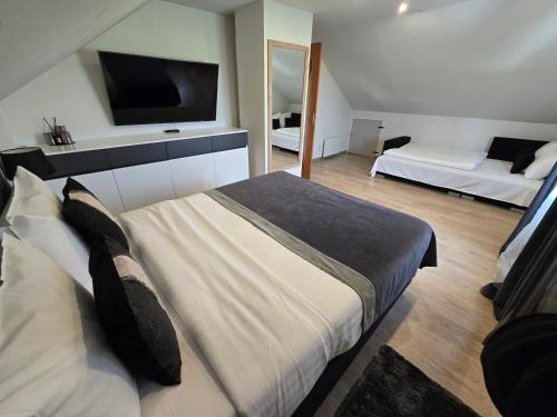 a bedroom with two beds and a tv on the wall at Vila Noruciai in Šašeliai