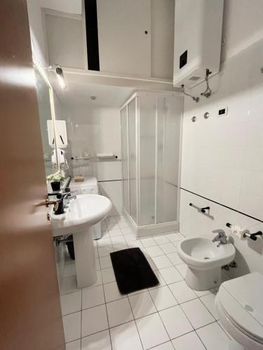 a white bathroom with a sink and a toilet at Wanderlust Guesthouse in Lamezia Terme