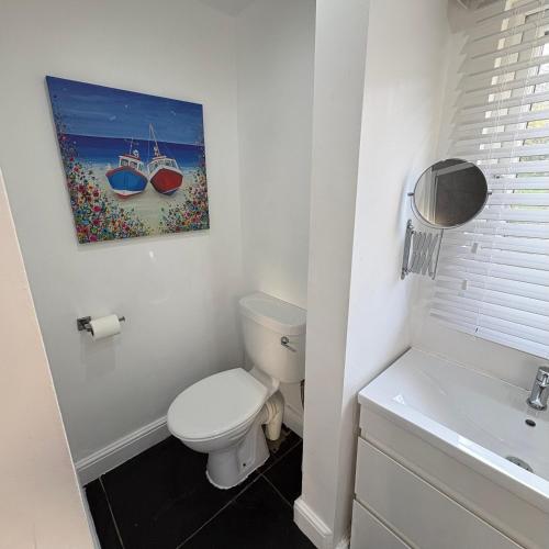 a bathroom with a toilet and a painting of boats at Santa's Cottage in Torquay