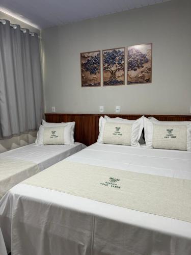 two beds in a room with three paintings on the wall at Pousada Paraiso valle verde in Estivado