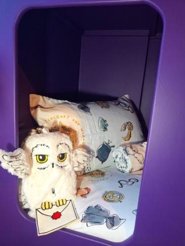 a stuffed owl is sitting on a bed at Rooms of Requirement in Watford