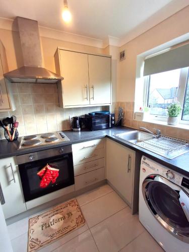 a kitchen with a stove top oven next to a dishwasher at Rooms of Requirement in Watford