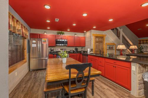 a kitchen with red cabinets and a wooden table at Bears Haven – Elegant 3 BR Chalet Game Area, Hot Tub, see through fire place in Gatlinburg