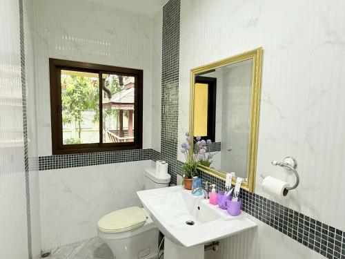 a bathroom with a sink and a toilet and a mirror at Yellow House Garden Pool Villa in Chiang Mai
