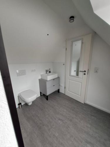 a white bathroom with a toilet and a sink at Ferienwohnung Hof Dittmer in Bleckede