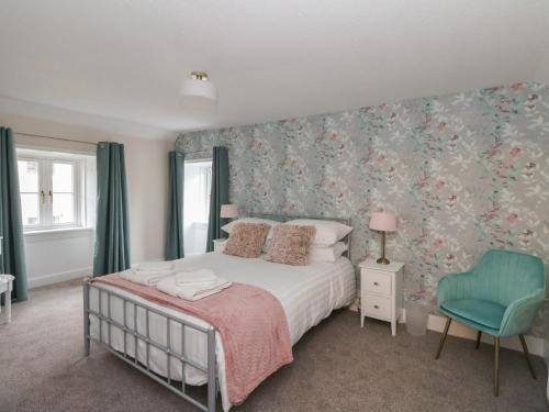 a bedroom with a bed and a blue chair at Pirnies in Pitlochry