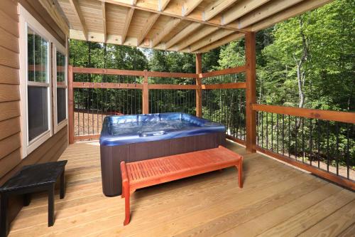 a jacuzzi tub on a deck with a bench at Luxury Chalet w Indoor Pool, Theater Room & Game Loft — 4 Miles to Gatlinburg in Gatlinburg