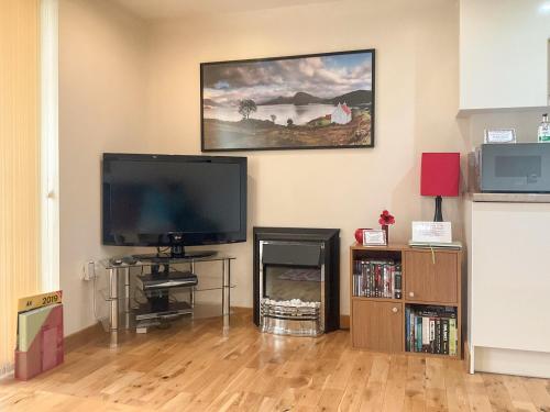 a living room with a flat screen tv and a fireplace at Thistle Dubh in Drumnadrochit
