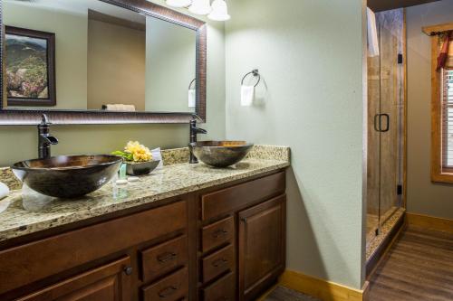 a bathroom with two sinks and a mirror at Gatlinburg Pool Pad – Luxury 4BR Chalet, Indoor Pool, Sauna & Theater Room in Gatlinburg