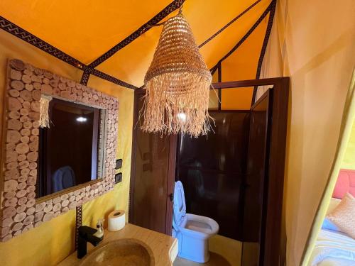 a bathroom with a toilet and a chandelier at Merzouga Infinity Dunes Camp in Merzouga