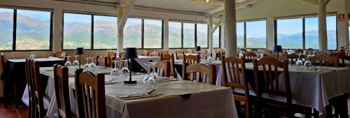 a room full of tables and chairs with mountains in the background at M&L Gerês in Salamonde