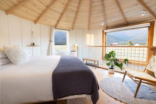 a bedroom with a bed and a chair and windows at Clark Farm Silos #4 - Scenic Mountain Views in Kalispell