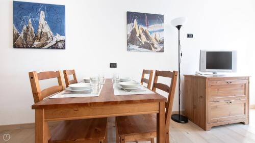 a dining room table with four chairs and a television at Plagheira 1 in Santa Caterina Valfurva