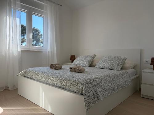 a white bedroom with a bed with two towels on it at Apartments Verde in Lumbarda