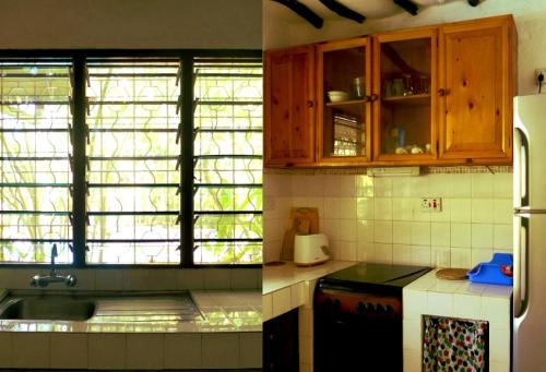 een keuken met houten kasten en een witte koelkast bij Frangipani Cottages in Diani Beach