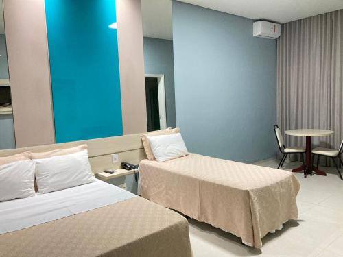 a hotel room with two beds and a table at Hotel Mirage in Vilhena