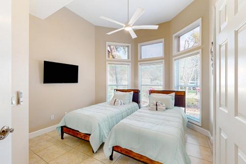 two beds in a room with a tv and windows at Golfer's Oasis w/ Pool in Black Diamond Ranch! in Lecanto