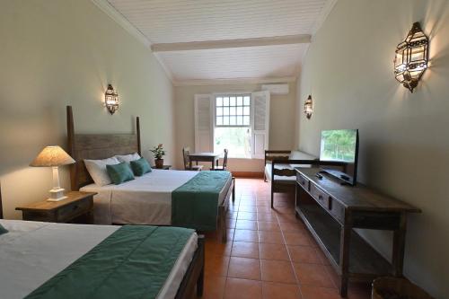 a bedroom with two beds and a desk and a television at Quinta das Águas by Summit Hotels in Itapira
