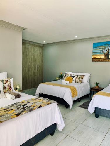 a bedroom with three beds with white sheets at Lady D Exclusive Abode in Polokwane