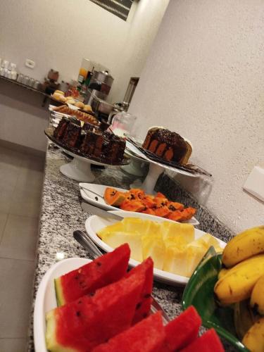 a counter top with plates of food and fruit at Hotel Lider in Paranaguá