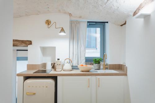 a kitchen with white cabinets and a sink and a window at Dimore Bianche, Santa Chiara in Putignano