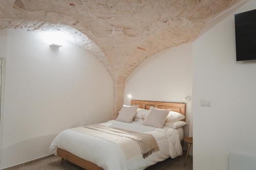 a bedroom with a white bed with a stone ceiling at Dimore Bianche, Santa Chiara in Putignano