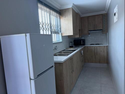 a kitchen with wooden cabinets and a white refrigerator at Saviour Apartments in Mthatha
