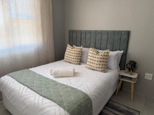 a bedroom with a large bed with white sheets and pillows at Saviour Apartments in Mthatha