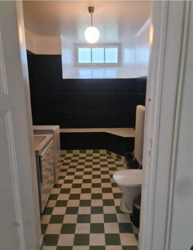 a bathroom with a toilet and a checkered floor at Nice and cosy flat in Molkom