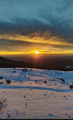 a snowy field with the sun setting in the background at SUNSET Villa PONIKVA in Kočani