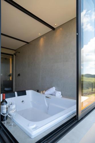 a bath tub in a bathroom with a glass window at Cabanas Horizonte Cambará Solare in Cambará
