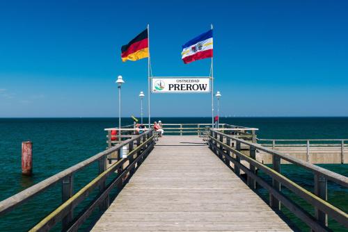 a wooden pier with two flags on top of the water at Ferienhotel Alter Bahnhof garni in Prerow