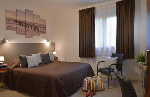 - une chambre avec un lit, un bureau et une chaise dans l'établissement Logis Hotel Le Prieure, à Saint-Marcel