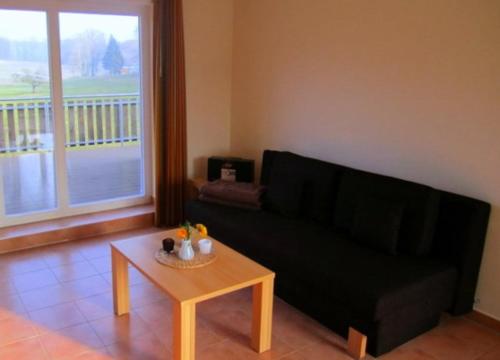 a living room with a black couch and a coffee table at Hotel Café Wahlde Restaurant in Neuenkirchen-Vörden