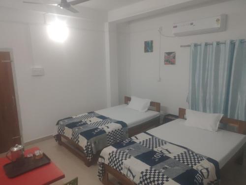 a room with two beds and a ceiling fan at Morisika lodge in Guwahati