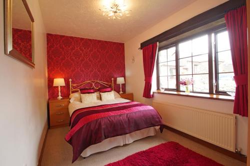 a bedroom with a bed and a red wall at Bodhyfryd in Llanfairpwllgwyngyll