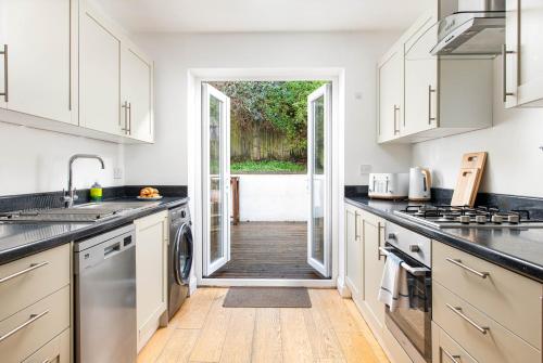 a kitchen with white cabinets and a door leading to a yard at Large 5Bed Town House-Sleeps 9-By FabAccommodation in Bristol