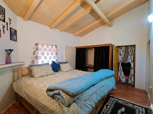 a bedroom with a bed with a blue blanket on it at Peak & Pine cottage in Almora