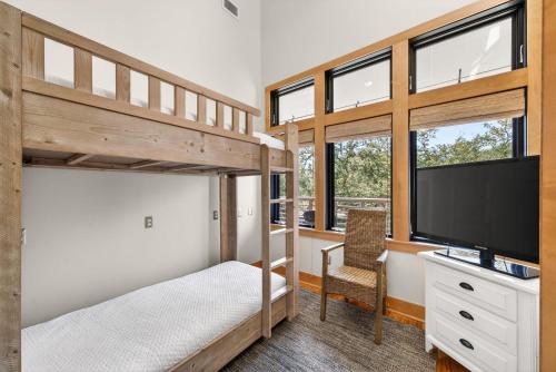 a bedroom with bunk beds with a tv and a desk at Brighton Cottage in Rosemary Beach