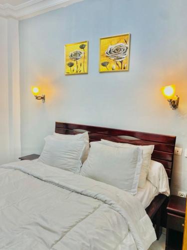 a bed in a bedroom with three pictures on the wall at KMC Guest House in Douala